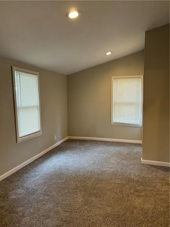 carpeted spare room featuring lofted ceiling