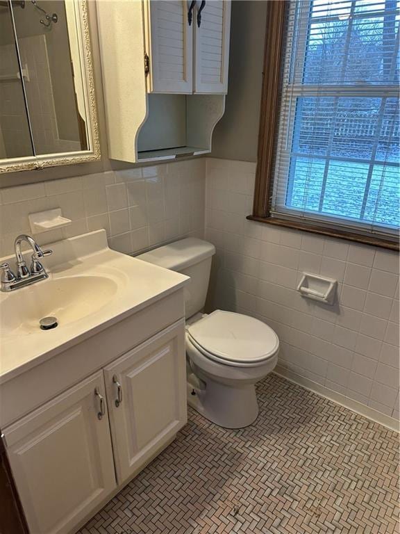 bathroom featuring toilet, a shower, tile walls, vanity, and tile patterned flooring