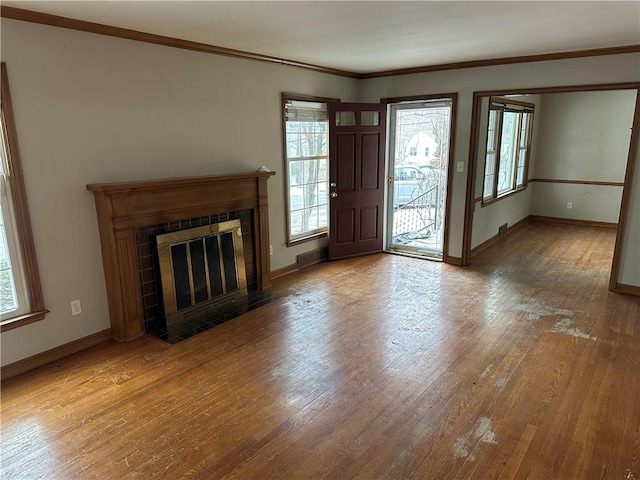 unfurnished living room with ornamental molding, wood-type flooring, and a tiled fireplace