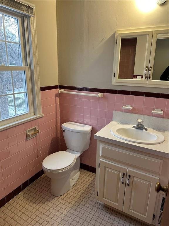 bathroom featuring vanity, tile walls, and toilet