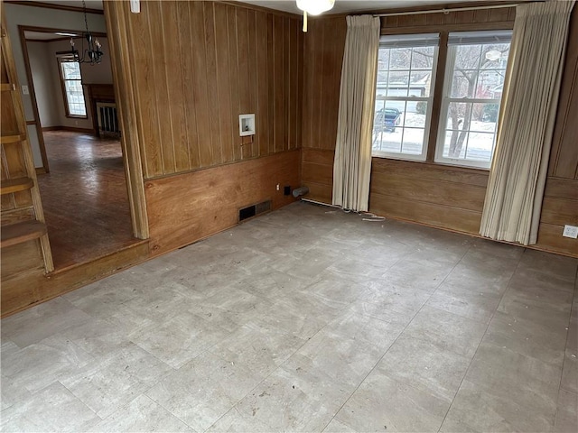 unfurnished room featuring a notable chandelier and wood walls