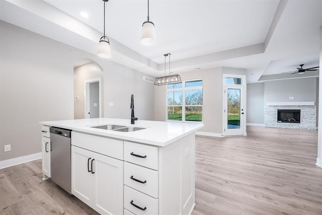 kitchen with white cabinetry, a kitchen island with sink, decorative light fixtures, a tray ceiling, and stainless steel dishwasher