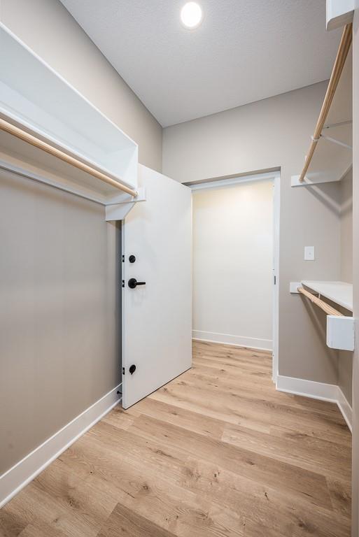 walk in closet with light hardwood / wood-style floors