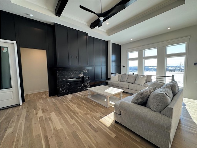 living room with ceiling fan, light wood-type flooring, and beam ceiling