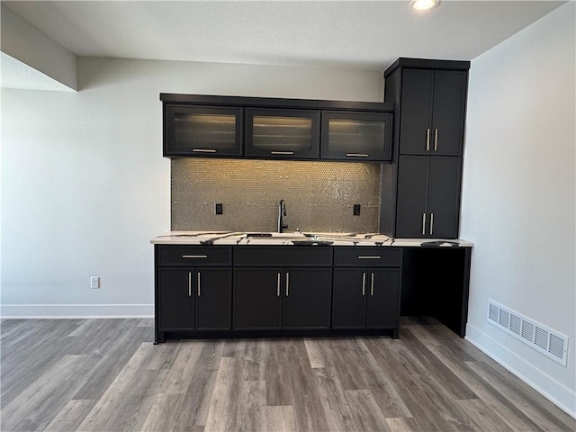 bar with sink, light hardwood / wood-style flooring, and tasteful backsplash