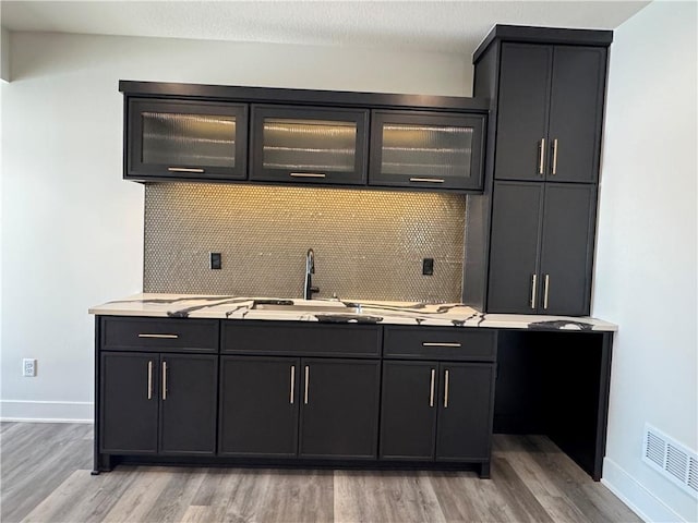 kitchen featuring sink, light hardwood / wood-style floors, and decorative backsplash