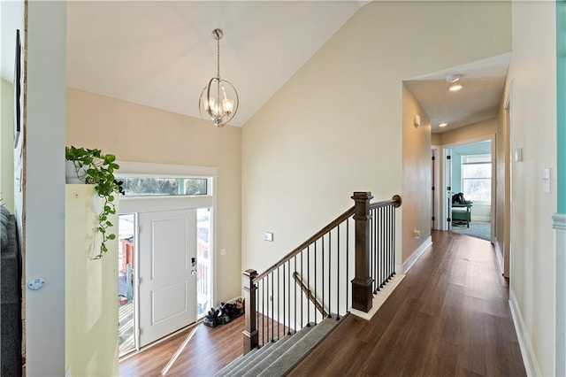 entrance foyer with a notable chandelier, dark wood-type flooring, and vaulted ceiling