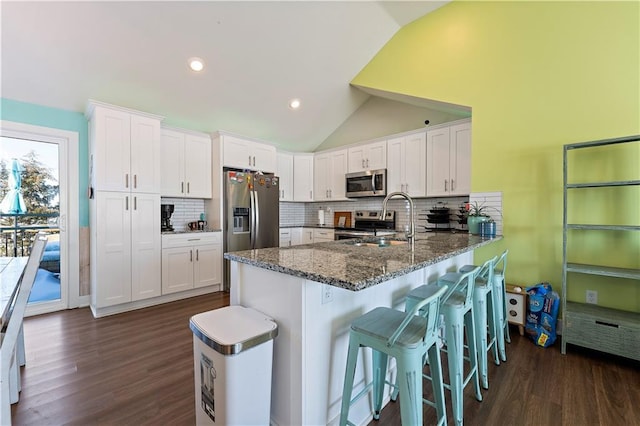 kitchen featuring kitchen peninsula, white cabinetry, stainless steel appliances, and vaulted ceiling