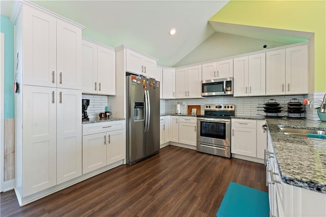 kitchen with backsplash, stainless steel appliances, vaulted ceiling, sink, and white cabinets