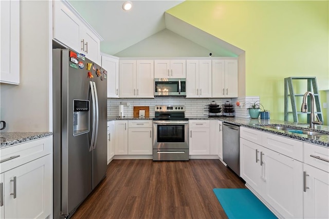 kitchen featuring sink, stainless steel appliances, lofted ceiling, decorative backsplash, and white cabinets