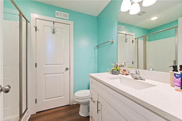 bathroom featuring toilet, vanity, a shower with shower door, and wood-type flooring