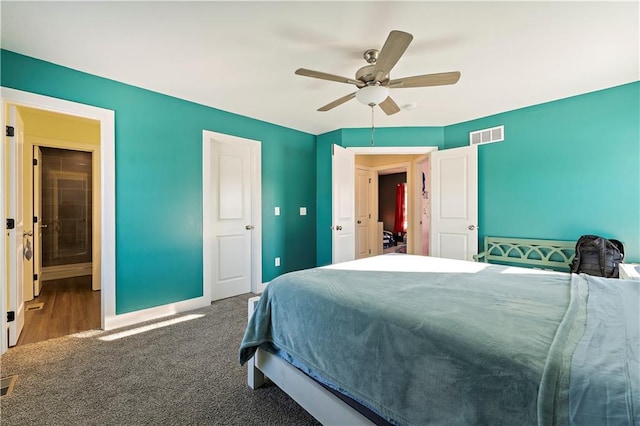 carpeted bedroom with ensuite bath and ceiling fan