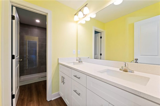 bathroom with hardwood / wood-style floors, vanity, and tiled shower