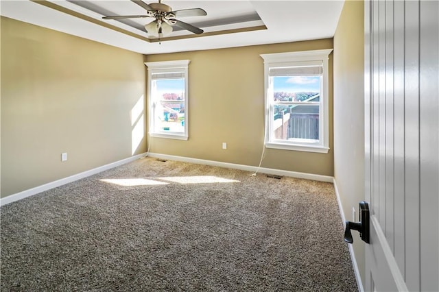 carpeted spare room with ceiling fan and a raised ceiling