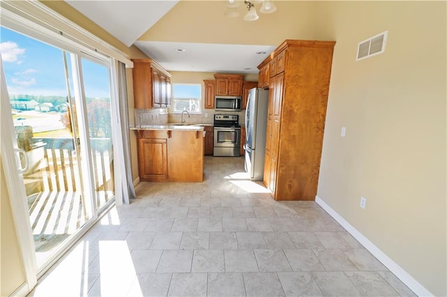 kitchen with sink, a chandelier, decorative backsplash, light tile patterned floors, and appliances with stainless steel finishes