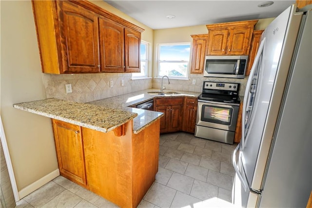 442 Redbud Ct, Warrensburg, MO 64093 - kitchen with appliances with stainless steel finishes, a peninsula, light stone counters, tasteful backsplash, and brown cabinets