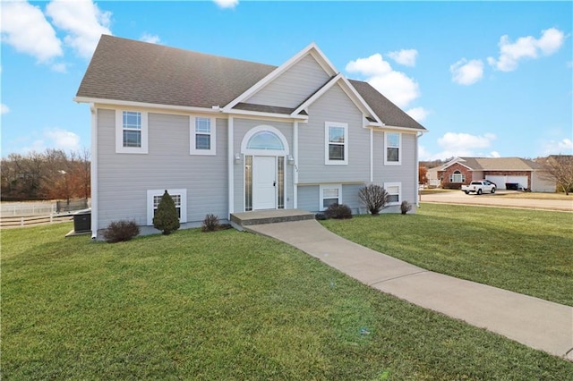 bi-level home with a garage, a shingled roof, fence, and a front yard