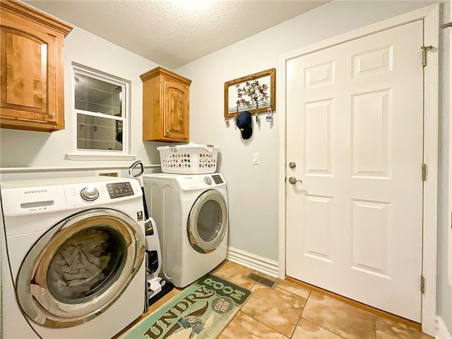 laundry area with washer and dryer, light tile patterned floors, cabinets, and a textured ceiling