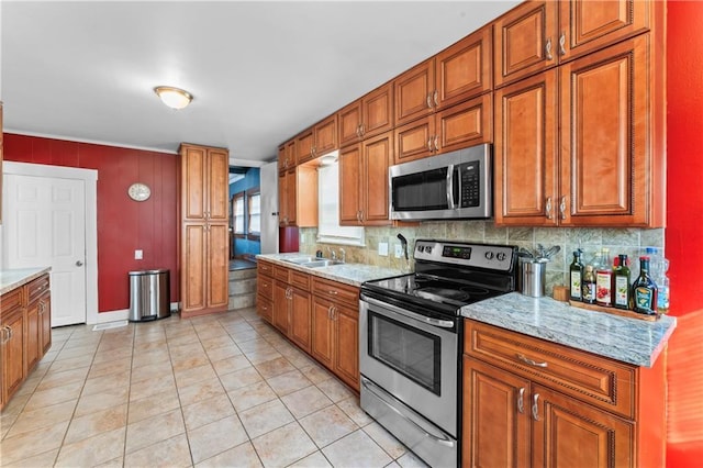 kitchen featuring appliances with stainless steel finishes, light tile patterned floors, light stone counters, and decorative backsplash