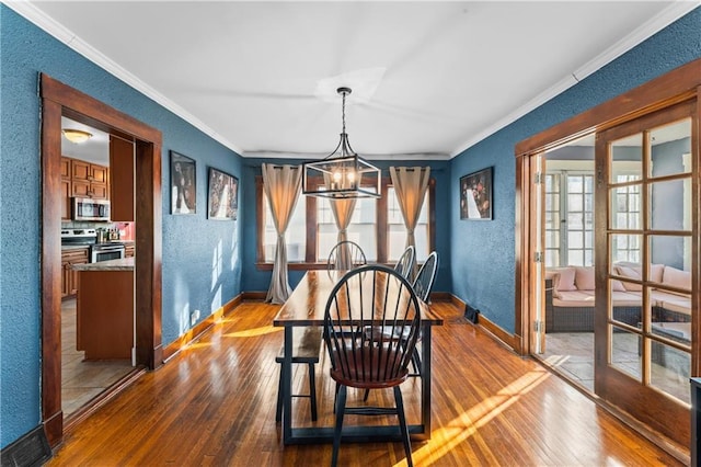 dining room with crown molding, a chandelier, and hardwood / wood-style floors