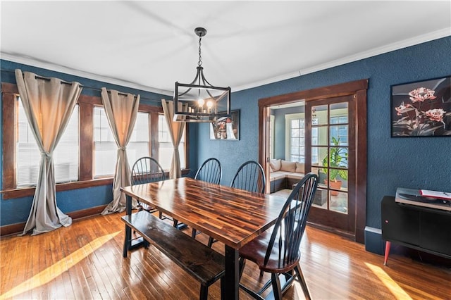 dining room with crown molding, hardwood / wood-style floors, and a notable chandelier