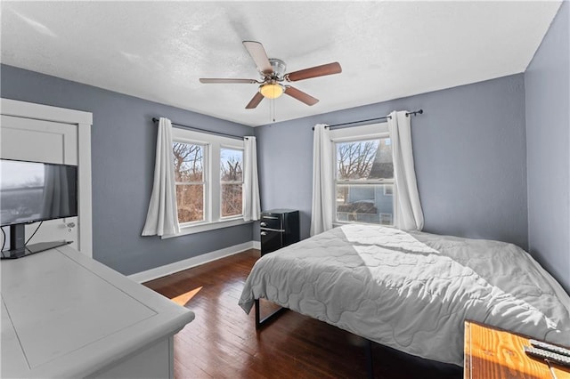 bedroom with ceiling fan, dark hardwood / wood-style flooring, and multiple windows