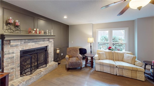 living room with a brick fireplace, hardwood / wood-style floors, and ceiling fan