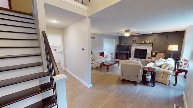 living room featuring ceiling fan, a fireplace, and light hardwood / wood-style flooring