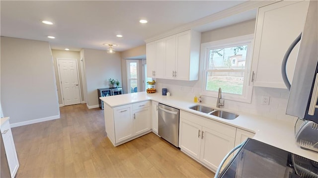 kitchen featuring white cabinets, stainless steel appliances, sink, kitchen peninsula, and light hardwood / wood-style flooring