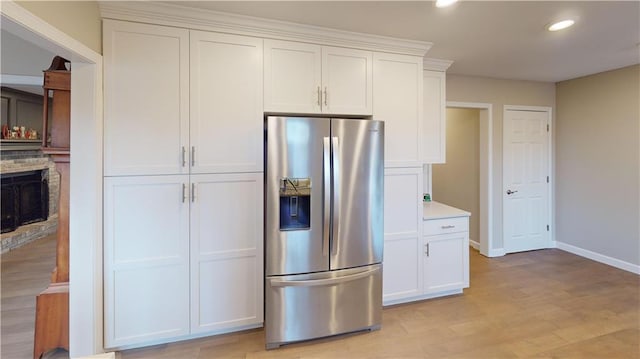 kitchen featuring a fireplace, white cabinetry, stainless steel fridge with ice dispenser, and light wood-type flooring