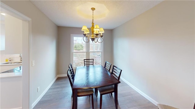 dining room with a textured ceiling, dark wood-type flooring, a chandelier, and sink