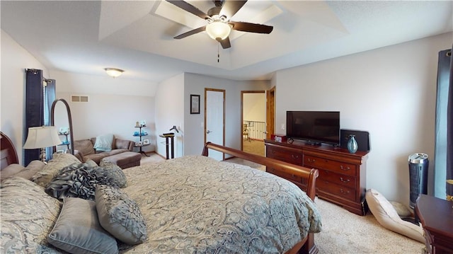 carpeted bedroom with ceiling fan and a tray ceiling