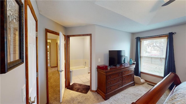 bedroom with light carpet, ceiling fan, and connected bathroom