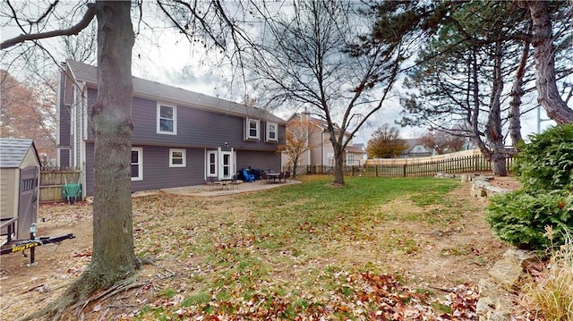 back of property with a lawn, a storage shed, and a patio