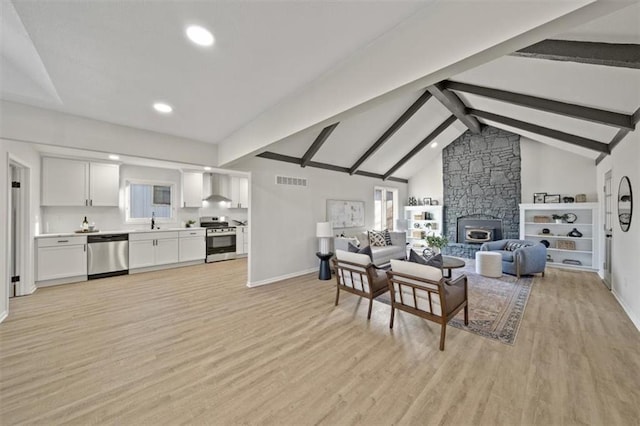 living room with beamed ceiling, high vaulted ceiling, light hardwood / wood-style flooring, and a healthy amount of sunlight