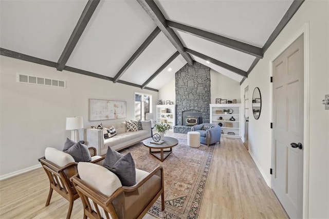 living room featuring beam ceiling, a stone fireplace, high vaulted ceiling, and light hardwood / wood-style floors