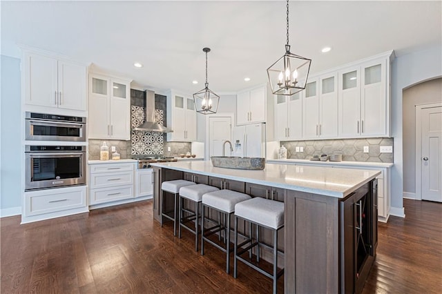 kitchen featuring stainless steel appliances, white cabinetry, a large island, and wall chimney exhaust hood