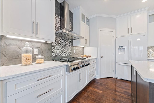 kitchen with white cabinetry, white refrigerator with ice dispenser, stainless steel gas cooktop, and wall chimney range hood