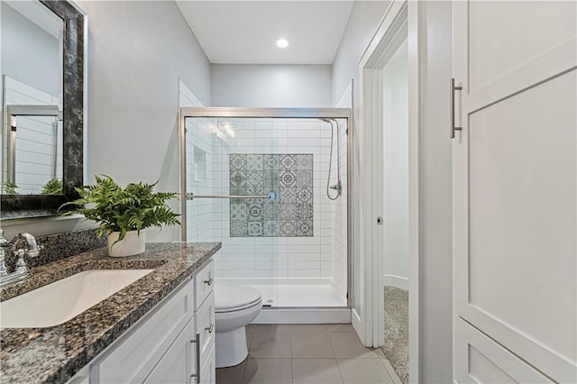 bathroom featuring toilet, vanity, tile patterned floors, and a shower with shower door