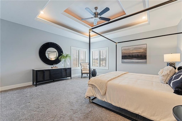 carpeted bedroom featuring a tray ceiling and ceiling fan