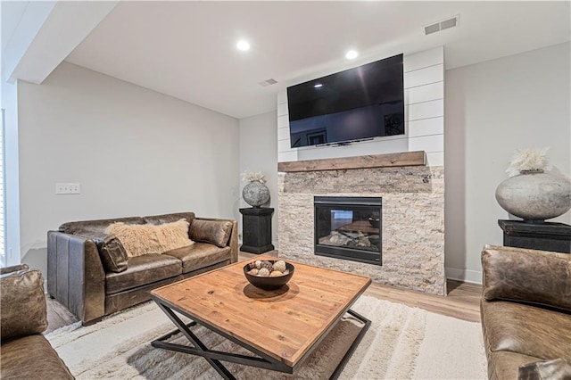 living room with a stone fireplace and light hardwood / wood-style floors