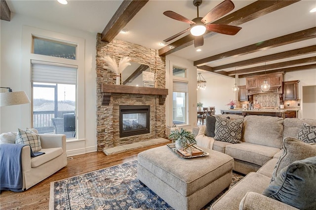 living room featuring beam ceiling, hardwood / wood-style flooring, a fireplace, and ceiling fan