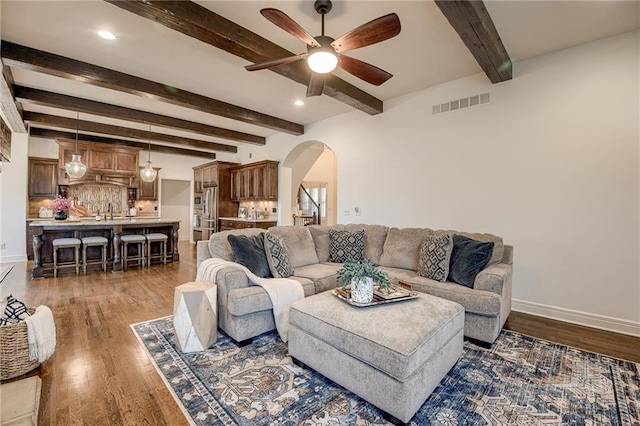 living room with dark hardwood / wood-style flooring, sink, beam ceiling, and ceiling fan