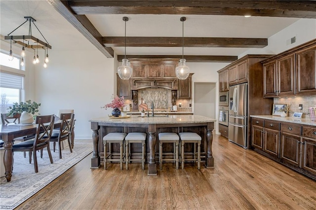 kitchen featuring decorative light fixtures, sink, hardwood / wood-style flooring, stainless steel appliances, and light stone countertops