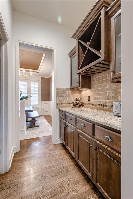 kitchen featuring light stone counters, dark brown cabinetry, light hardwood / wood-style flooring, and backsplash