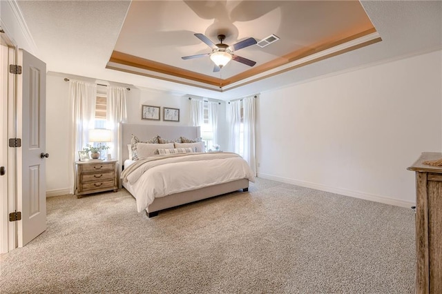 carpeted bedroom featuring a raised ceiling, crown molding, and ceiling fan