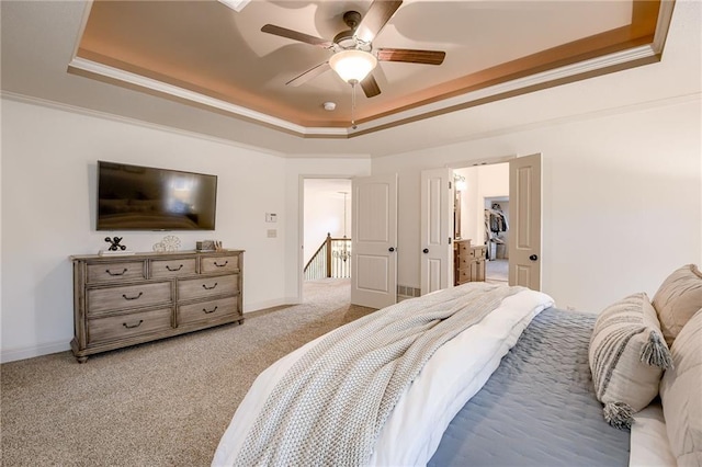 bedroom featuring ceiling fan, light colored carpet, ornamental molding, and a tray ceiling