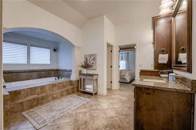 bathroom with vanity, a relaxing tiled tub, vaulted ceiling, tile patterned floors, and ornate columns