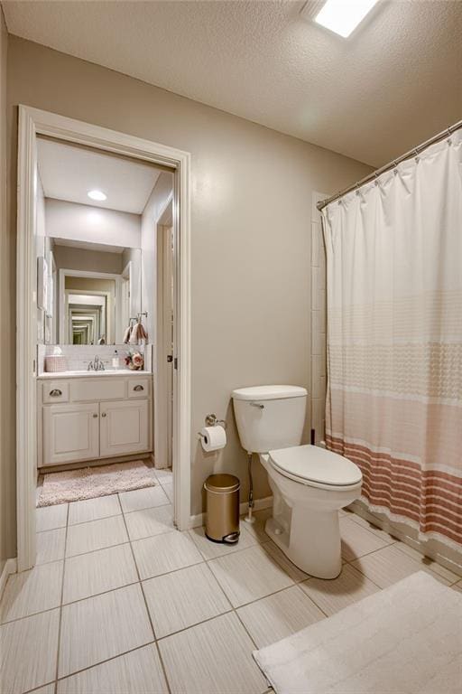 bathroom featuring tile patterned flooring, vanity, toilet, a textured ceiling, and a shower with shower curtain