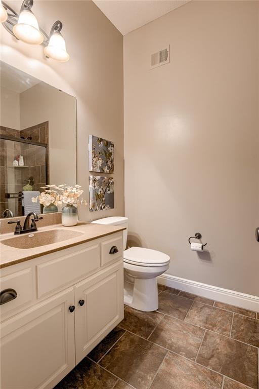 bathroom featuring walk in shower, vanity, and toilet